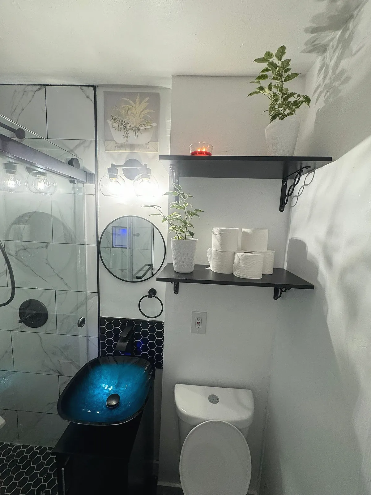 Bathroom shelf detail with rolled towels, a round mirror and a potted plant