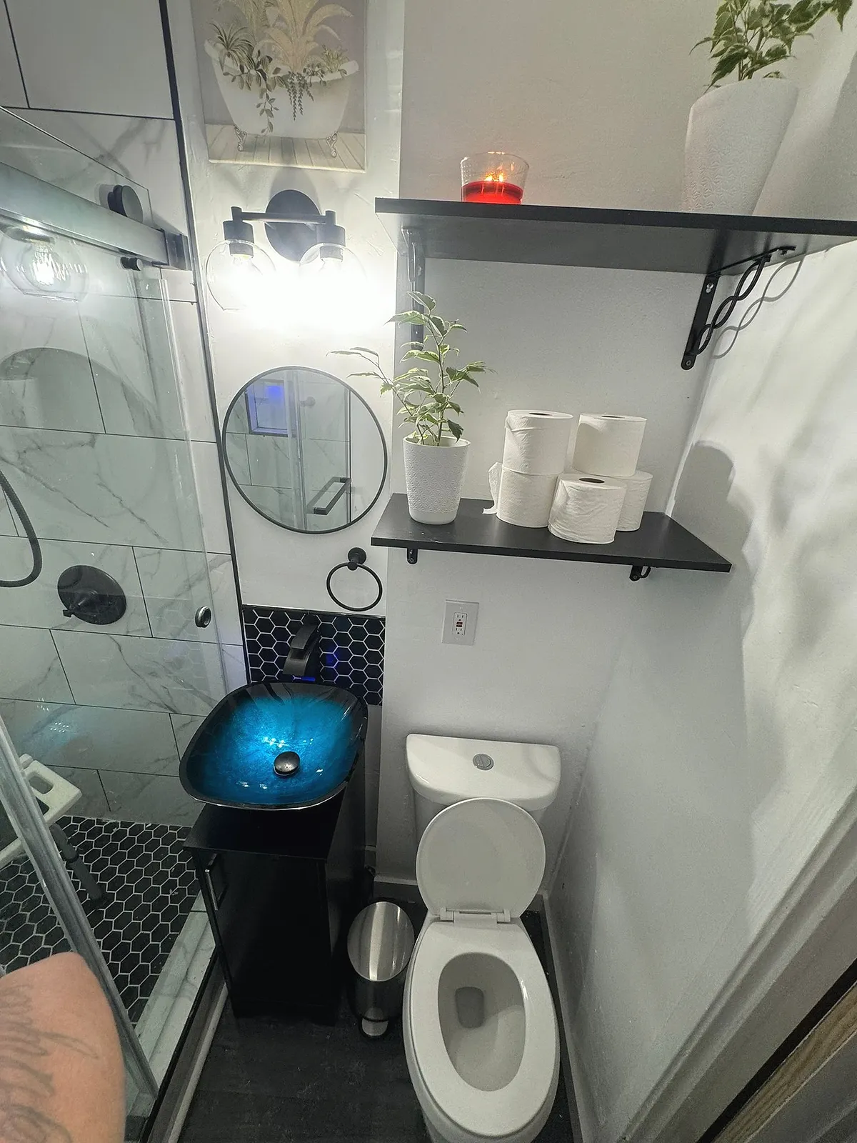 Bathroom with a glass shower screen, dark shelving and folded towels