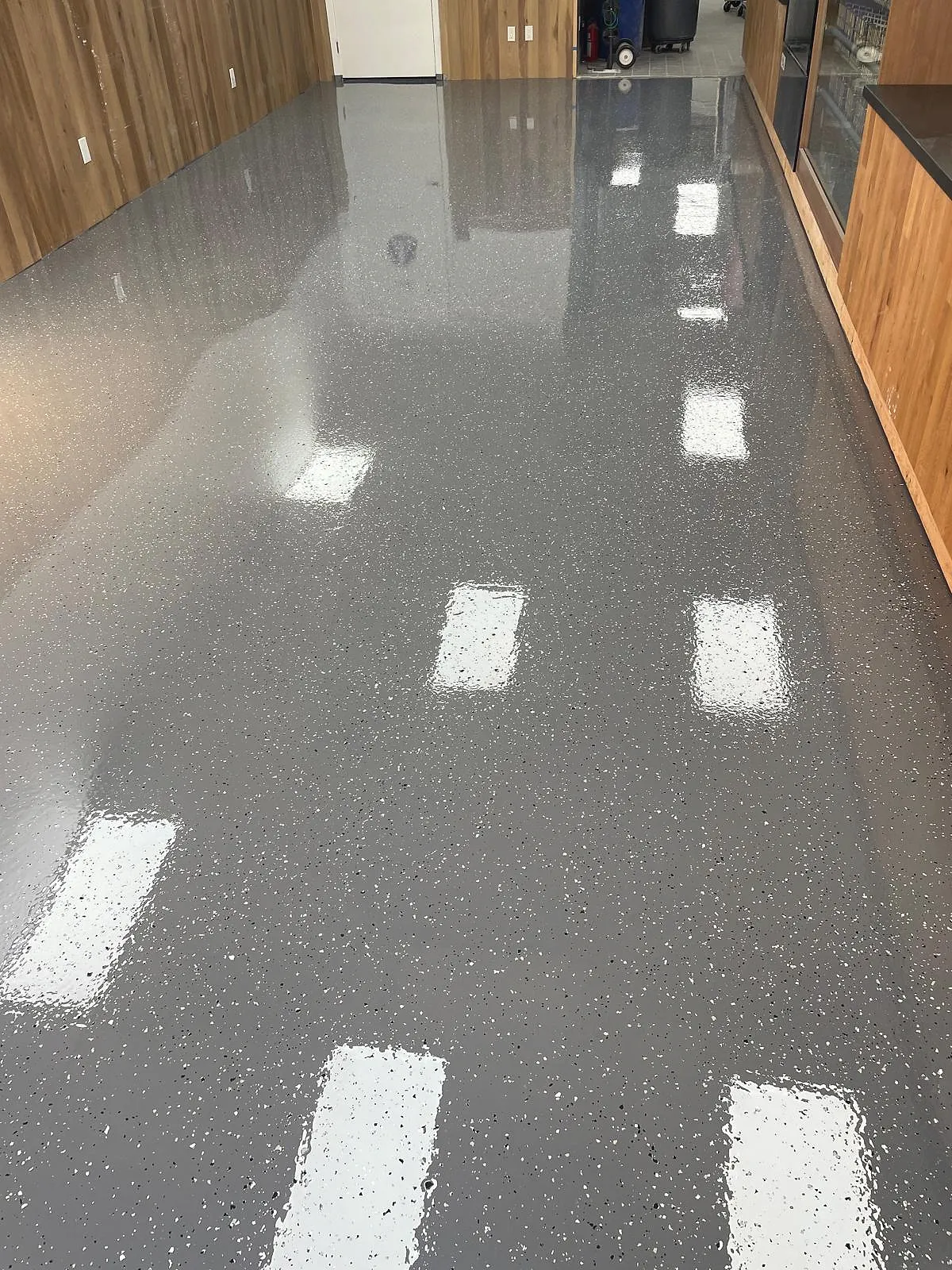 Finished grey flake epoxy floor with a high-gloss reflective surface in a commercial interior