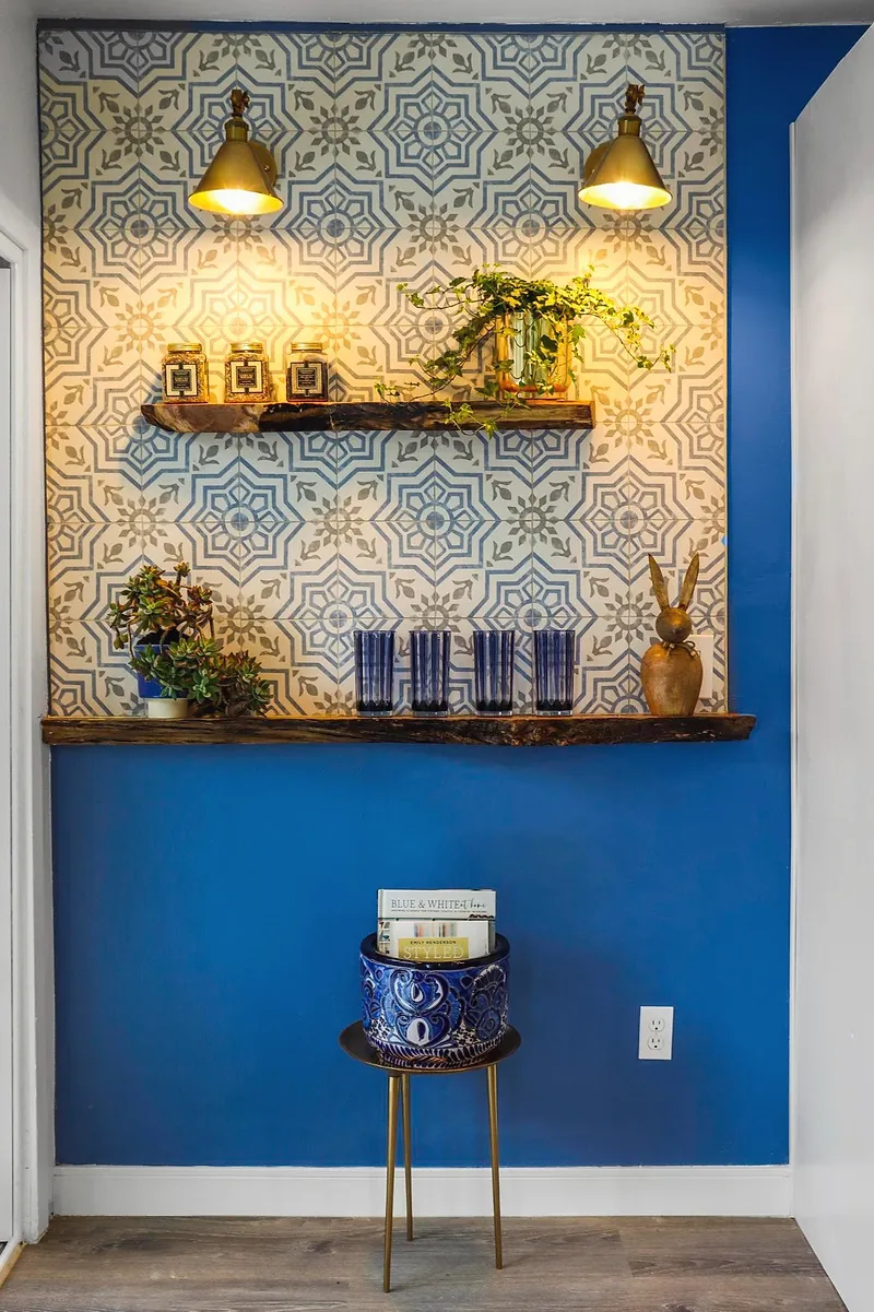 Patterned cement-tile feature wall with a live-edge timber shelf against a deep blue kitchen wall