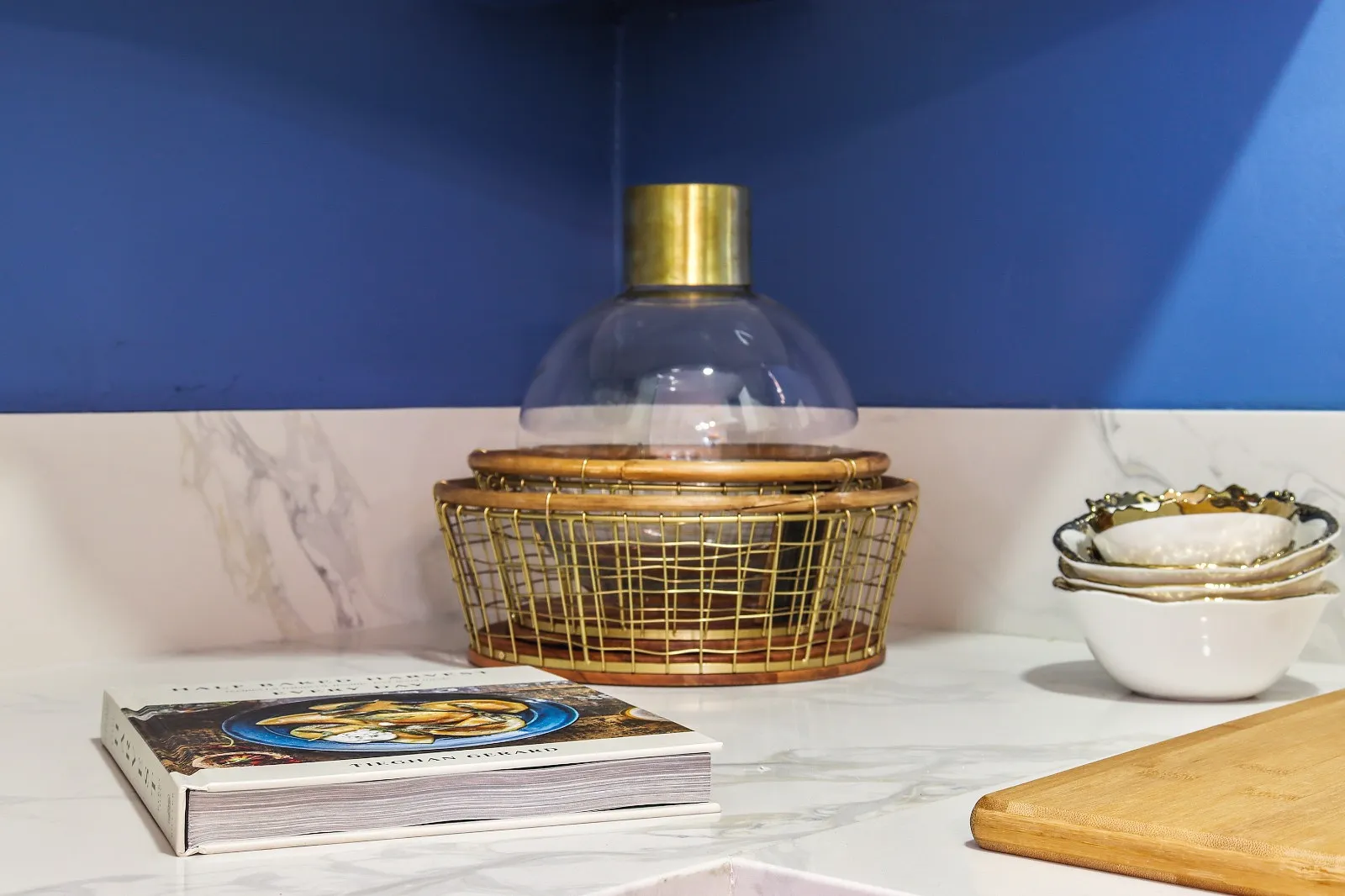 Marble-look quartz worktop detail with a brass cloche and serving board